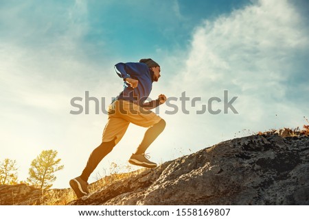 Skyrunner athlete runs uphill against sunset or sunrise sky and sun. Skyrunning concept Royalty-Free Stock Photo #1558169807