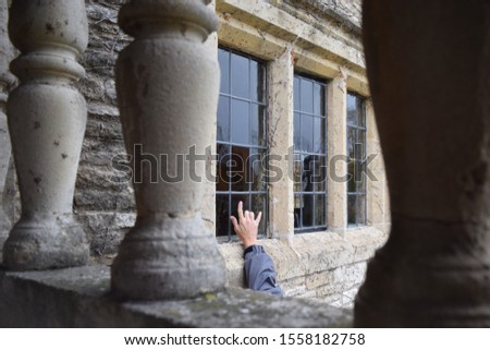 Hand signing love in sign language through a window. Secret admirer, deaf and mute community, universal language. Rustic house with vintage windows. Column in the forefront