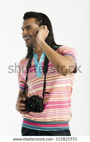 Photographer holding a digital camera and talking on a mobile phone