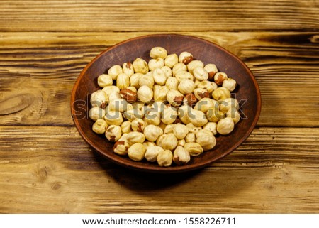 Peeled hazelnuts in ceramic plate on wooden table