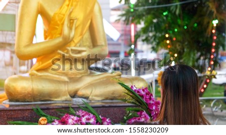 beautiful asian woman praying Buddha statue with purple flower