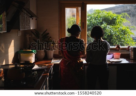 Cooking traditional Indian snack, mother and daughter. Royalty-Free Stock Photo #1558240520