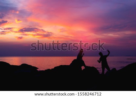 Silhouette of lovers and sunset background in the summer.