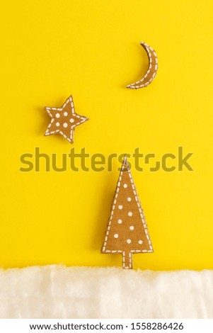 Christmas card with a picture of a Christmas tree made of cardboard in the snow of wool on a yellow background. Minimalism concept