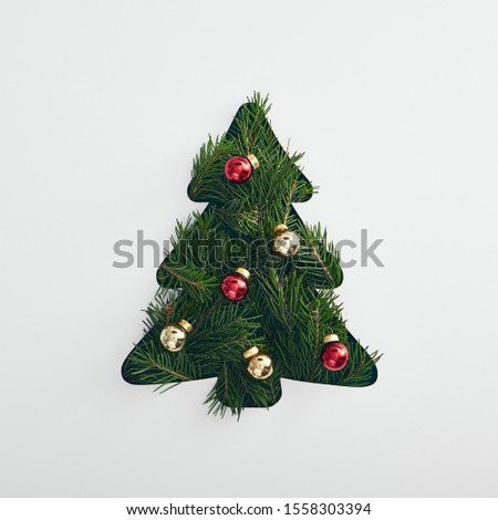 Christmas minimal concept - creative christmas tree made from evergreen branch and bauble. Mockup with green christmas tree flatlay on white background for concept design. Xmas tree geometric shape. 