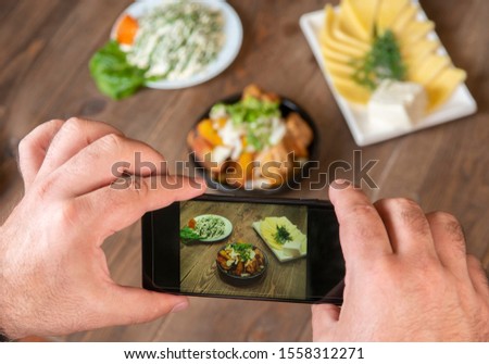 Food blogger using smartphone taking photo .Mans hands make phone photography of traditional meals. lunch or dinner.meat and potatoes. For social media, blogging. Top view mobile phone.