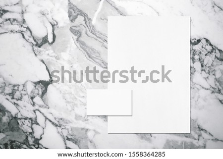 Empty white vertical a4 sized poster and horizontal rectangle business card mockup with soft shadows on grey marble background. Flat lay, top view