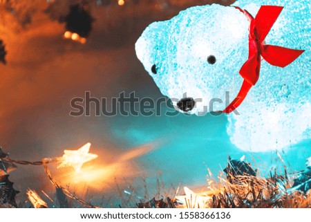 Christmas background with a luminous bear.
Glowing bear with a red bow close-up.