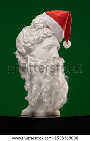 White plaster Statue of Apollo Belvedere with a long white beard and in a red cap of Santa Claus