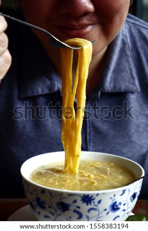 Photo of beautiful Asian woman eating freshly cooked Lomi or fat egg noodles with soup