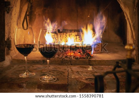 Glasses with red wine at the fireplace, romantic evening in a cozy home