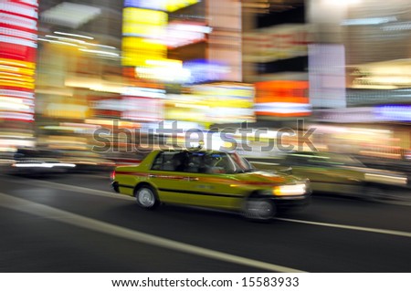 Panned image of Japanese taxi with bright, colorful lights in the background.