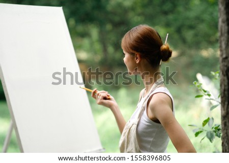 young woman in nature draws a picture