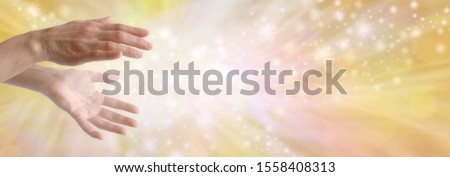 Sending out beautiful golden healing energy - female hands with sparkling white light flowing outwards against a wide golden orange yellow flowing energy background with copy space
 Royalty-Free Stock Photo #1558408313