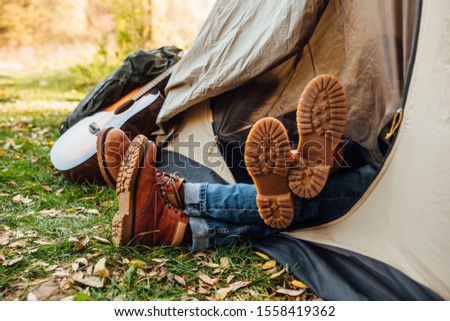 Close up photo of 
hiking boots. Young beautiful couple sleeping in the tent. Beautiful morning in camp in the forest in nature.