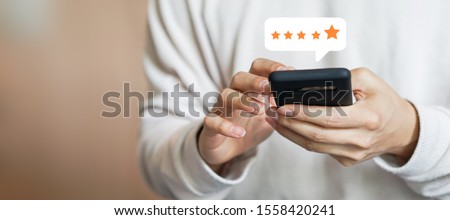 close up on customer man hand pressing on smartphone screen with gold five star rating feedback icon and press level excellent rank for giving best score point to review the service , business concept Royalty-Free Stock Photo #1558420241