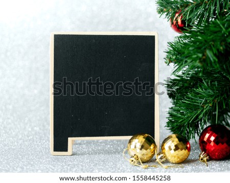 Blank blackboard on silver glitter with christmas tree background.