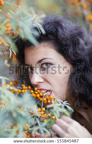 Zoomed view of woman bite gooseberries from branch