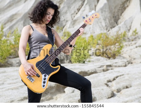 Woman on sandy background posing with yellow guitar