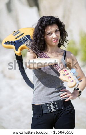 Woman with guitar over shoulder on sandy background