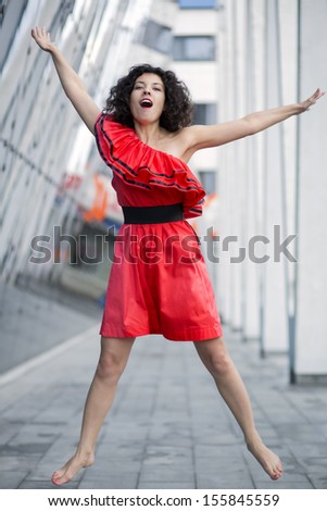 Woman in red dress jump both hands up