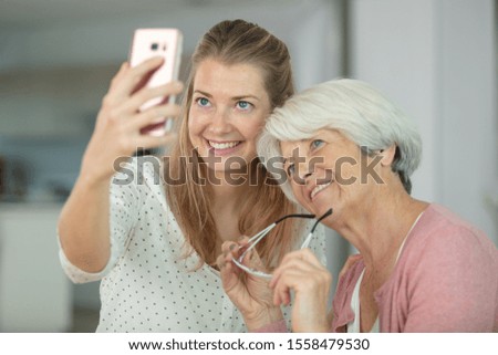 senior mother and daughter taking selfie having fun at home