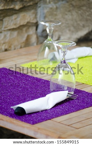 Table serving with wine glasses and bright napkins in street cafe