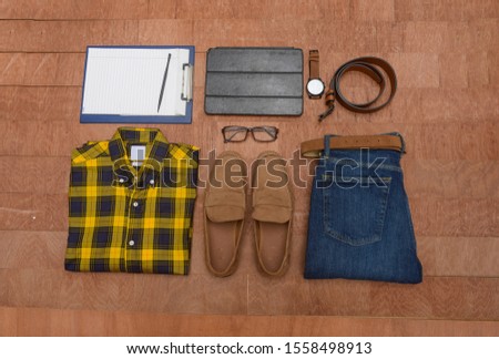 Men's casual outfits with man accessories,tablet, on brown wooden board background
