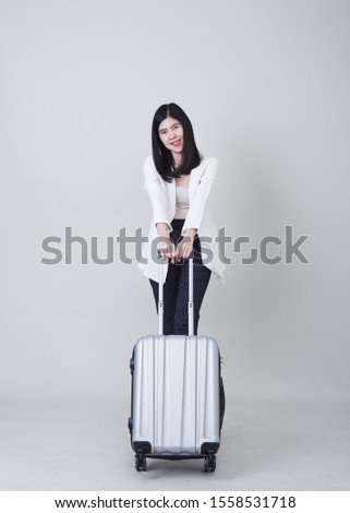 Beautiful young asian woman tourist smiling and pulling gray color luggage to travel on his vacation isolated on light gray studio banner background with copy space for text