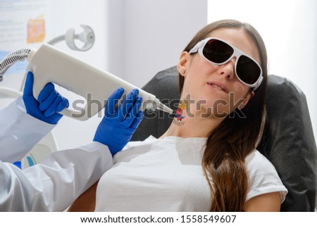Woman bites her lip during a tattoo removal procedure. A little bit painful, but safe. Free from the mistake of youth. Royalty-Free Stock Photo #1558549607