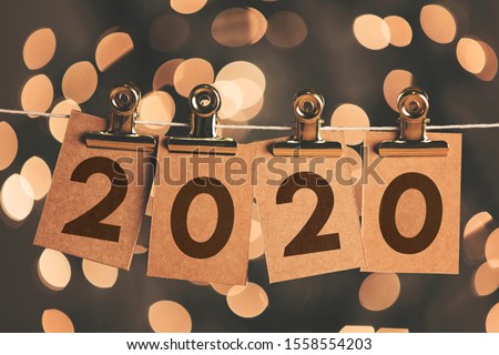 2020 new year sign pegged to a string with bokeh lights in the background