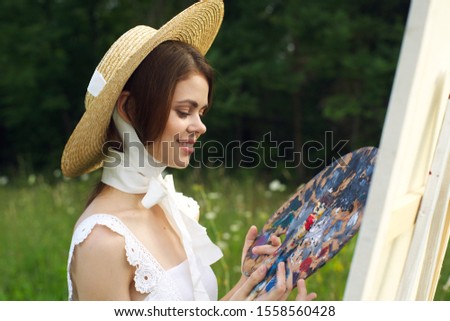 young woman in a forest grove an easel paints a picture