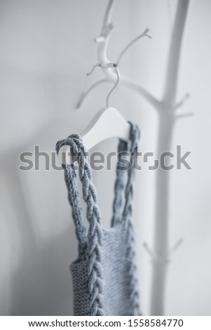 Knitted clothing made of sheep wool for young children who were just born. Hanging on a hanger on a deckboard tree on a white background.