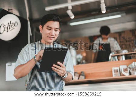 portrait of male coffee cafe owner use a tablet to receive orders from customers. Royalty-Free Stock Photo #1558659215