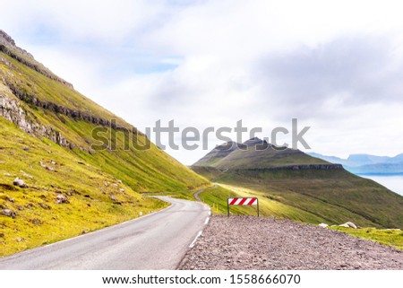 Road travel picture of Faroe Islands. Green mountains with great clouds above.
