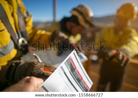 Defocused of construction worker wearing a industry safety glove signing off high risk working at heights permit on the opening field prior starting early day shift 