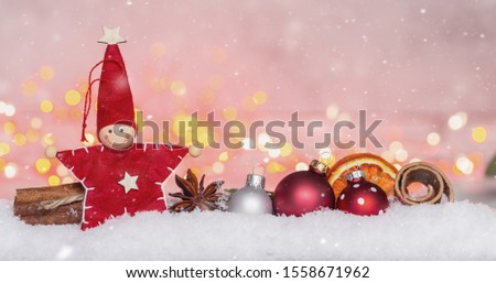 Christmas decoration with star and christmas balls and cinnamon stick with colorful lights and bokeh on snow and concrete background