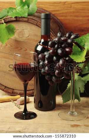 Still life with wine bottles, one glass of red wine, grapes  and oak barrel  