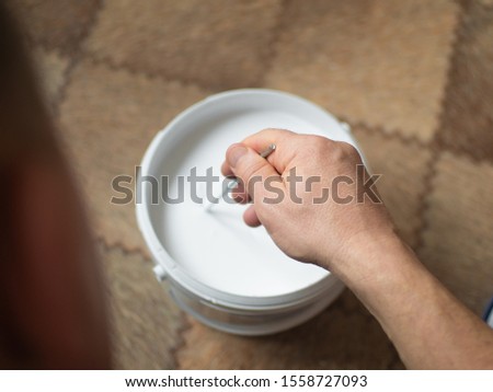 a man mixes paint in a bucket
