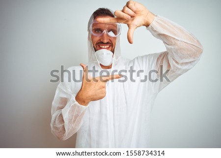 Painter man wearing professional worker equipment protection over isolated background smiling making frame with hands and fingers with happy face. Creativity and photography concept.