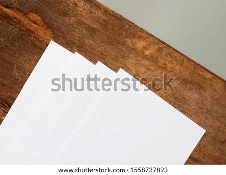 Several sheets of white paper on a wood background.