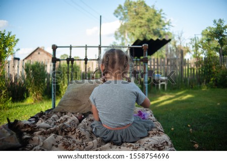 
girl sits with her back on an old bed near the apple tree. fabulous picture