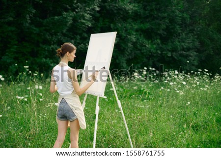 woman model easel paints a picture with paints