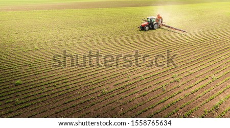 Tractor spraying pesticides on soybean field  with sprayer at spring Royalty-Free Stock Photo #1558765634