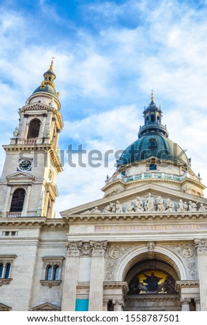 Vertical picture of the front side facade of Saint Stephen's Basilica in Budapest, Hungary with blue sky and clouds above. Roman Catholic basilica built in neoclassical style. Left tower and cupola.