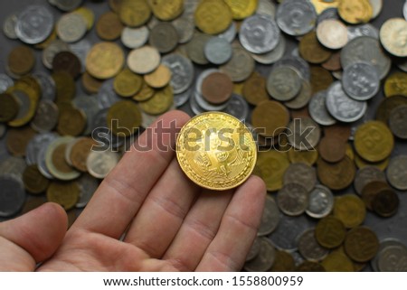 a guy holds a bitcoin in his hand against the background of money