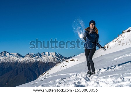 Happy young woman playing snowball fight on the snow day. Winter concept.