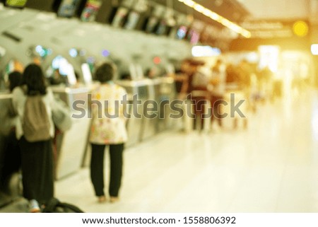 Defocused group of passengers checking in at the row of counter for boarding pass at airport. Blurred picture in purpose