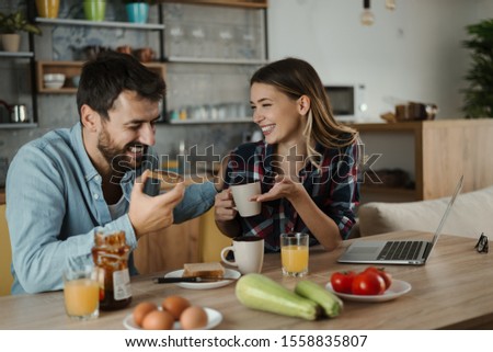Young cheerful couple having fun during breakfast time in the kitchen.