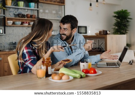 Young happy couple enjoying in breakfast time and surfing the net on laptop